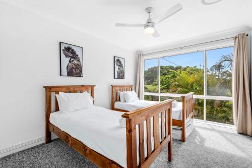 two beds in a bedroom with a window at Paradise Waters 13 in Coffs Harbour