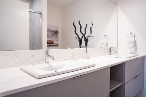 a white bathroom with a sink and a mirror at Tucker's Place in Revelstoke
