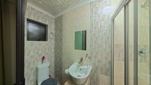a bathroom with a toilet and a sink and a shower at Kings Rest Bed And Breakfast in Gaborone