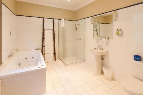 a bathroom with a tub and a toilet and a sink at Glen Erin at Lancefield in Rochford