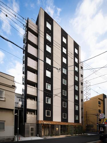 a tall black and white building on a street at R Hotel Namba East in Osaka