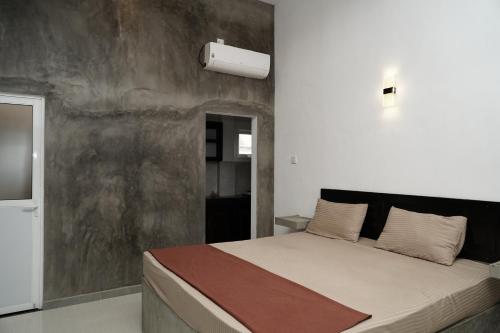 a bedroom with a large bed with a concrete wall at Rugee R Villa in Negombo