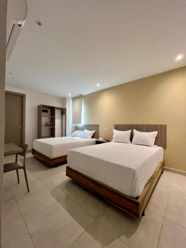 a bedroom with two beds and a desk and a chair at BQ84 Urban Hotel in Barranquilla