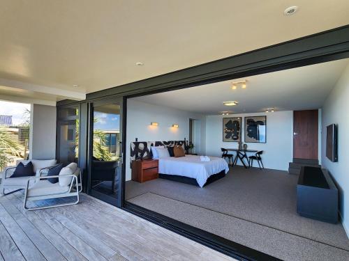 a master bedroom with a bed and a balcony at Dreamtime Hahei in Hahei
