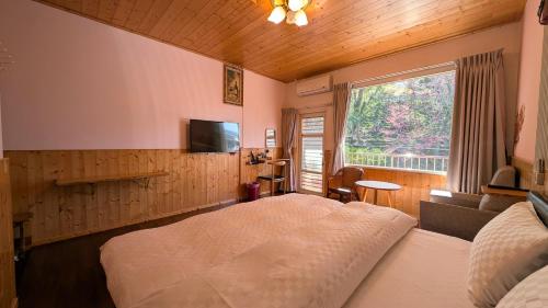 a bedroom with a bed and a tv and a window at Chingjing ‧ orange Scotia in Ren'ai