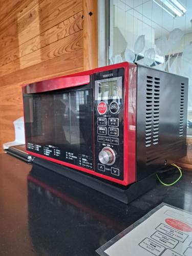 a red microwave sitting on top of a counter at 宿小町や in Senboku