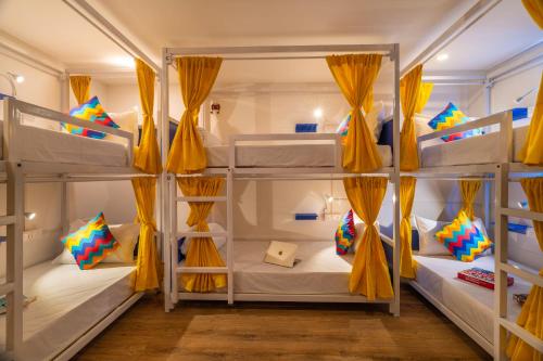 a room with four bunk beds with yellow drapes at goSTOPS Bengaluru, Indiranagar - Private Rooms & Dorms in Bangalore