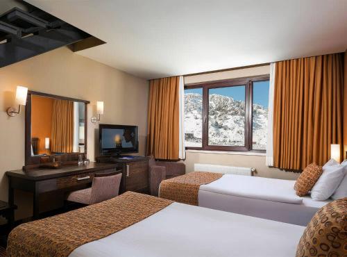 a hotel room with two beds and a desk at Barida Hotels Davraz in Cobanisa