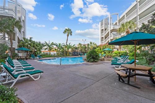 a pool with lounge chairs and a table and an umbrella at Luxury Beach front Condo in Galveston