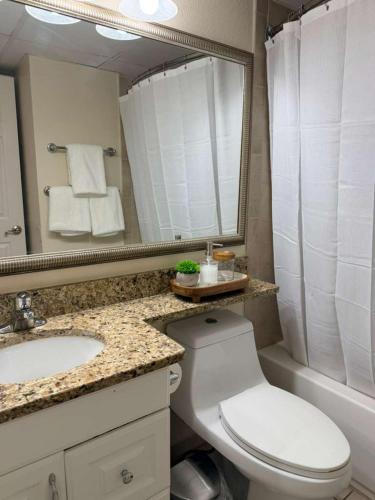 a bathroom with a toilet and a sink and a mirror at Luxury Beach front Condo in Galveston