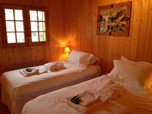 two beds in a room with wooden walls and windows at Chalet Marie Blanche in Saint-Gervais-les-Bains