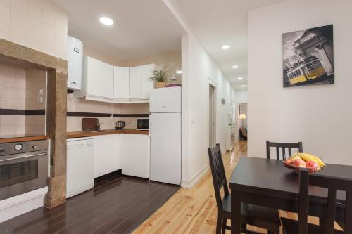 a kitchen with white cabinets and a dining room table at Elite House in Lisbon