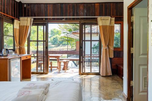 a bedroom with a bed and a balcony with a table at De Bua Valley Resort in Wang Nam Khieo