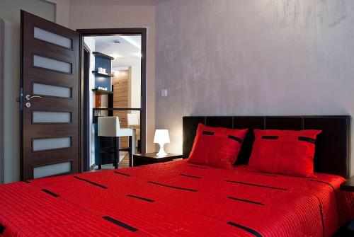 a red bed with red pillows in a bedroom at Apartament Perłowy in Krynica Zdrój