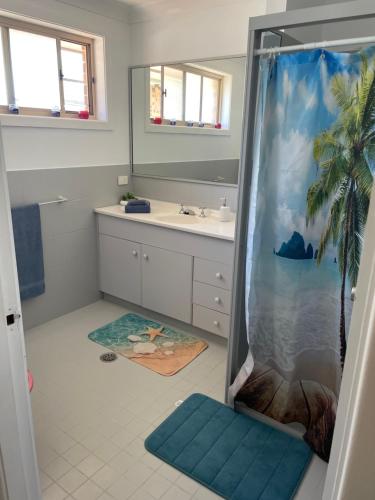 a bathroom with a shower with a palm tree at Tuncurry tranquility PID -STRA - 59456 in Tuncurry