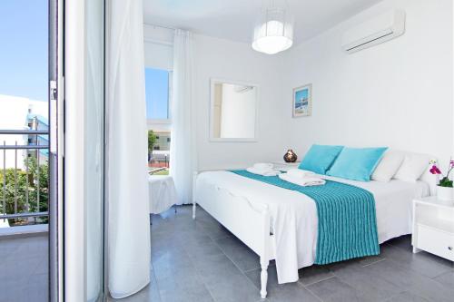 a white bedroom with a bed and a balcony at Villa Solebianco Protaras in Protaras