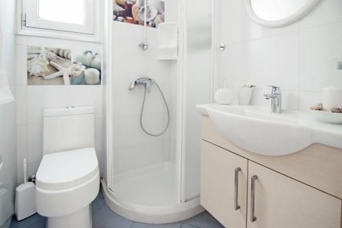 a white bathroom with a toilet and a sink at Villa Solebianco Protaras in Protaras