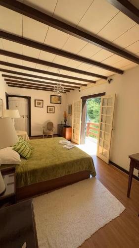 a bedroom with a green bed and a large window at Casa do Fachoalto in Petrópolis
