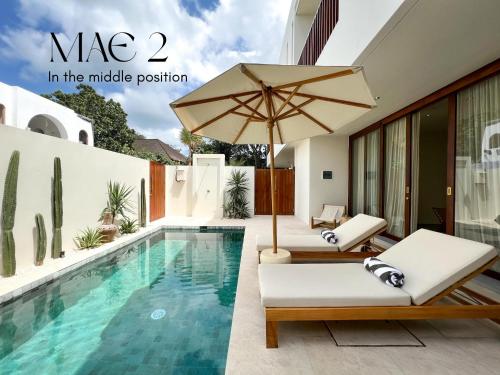 a villa with a swimming pool and an umbrella at MAE Villas Canggu in Canggu