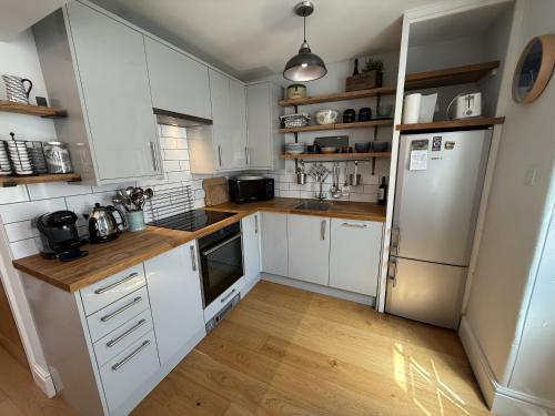 a kitchen with white cabinets and a refrigerator at Highfield Terrace – Cosy Devon Retreat, Close to Beer Beach in Beer
