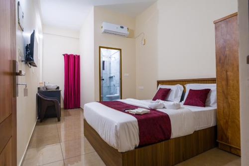 a bedroom with a large bed with red pillows at Hotel Aeronest Residency in Calicut