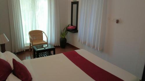 a bedroom with a bed and a chair and a window at Mayas Beach House in Mararikulam