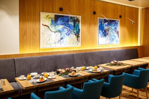 a dining room with wooden tables and blue chairs at HVD Grand Hotel Suhl Business & Leisure in Suhl