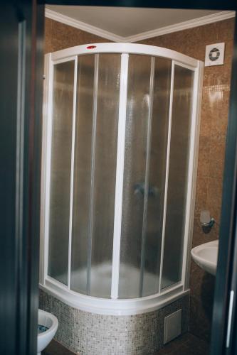 a glass shower in a bathroom with a sink at Fermerska Hata in Dubno