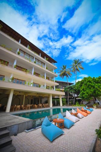 a resort with a pool and chairs and palm trees at Kingfisher Beach in Unawatuna
