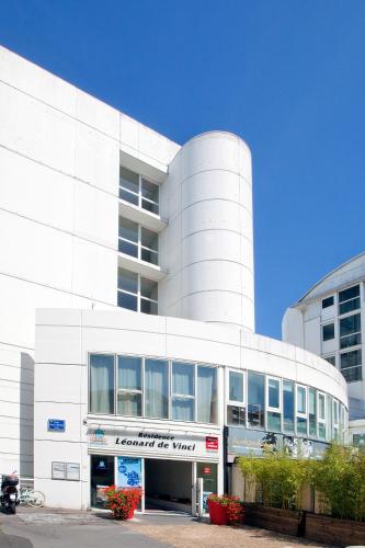 - un grand bâtiment blanc avec un panneau devant dans l'établissement Séjours & Affaires Tours Léonard De Vinci, à Tours