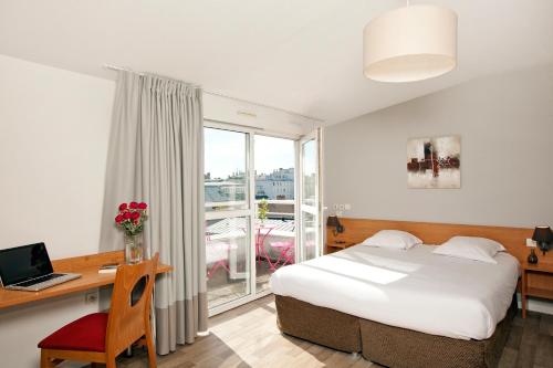 a hotel room with a bed and a desk and a window at Séjours & Affaires Tours Léonard De Vinci in Tours