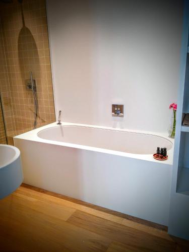 a white bath tub in a bathroom with a shower at b&b les invités in Bruges
