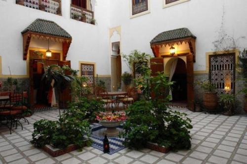 un cortile con tavoli, sedie e piante in un edificio di Riad Dalia a Marrakech