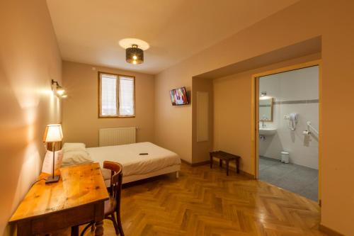 a bedroom with a bed and a table and a bathroom at Hotel Des Alpes in Le Bourg-dʼOisans