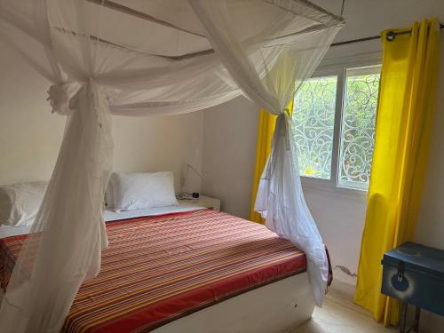 a bedroom with a bed with a canopy and a window at Downtown Malindi Apartment in Malindi