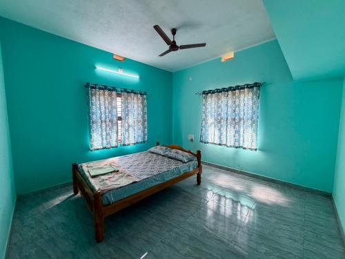 a blue room with a bed and two windows at Laksh Nivas Fields Stay in Udupi