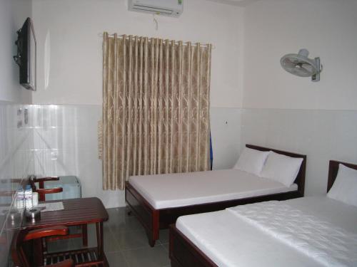 Habitación con 2 camas, mesa y ventana en Hoa Sua Motel, en Long Hai
