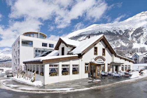 ein Gebäude mit einem schneebedeckten Berg im Hintergrund in der Unterkunft Hotel Station in Pontresina