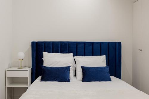a bed with a blue headboard and white pillows at Lisbon Nest 2BR in Lisbon