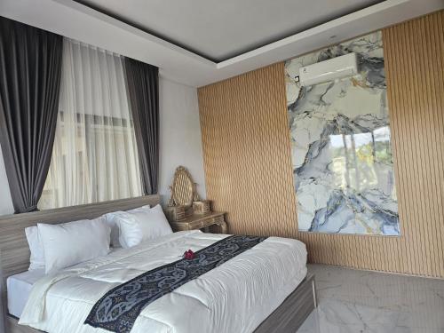 a bedroom with a large bed with a painting on the wall at Arkana Homestay in Tabanan