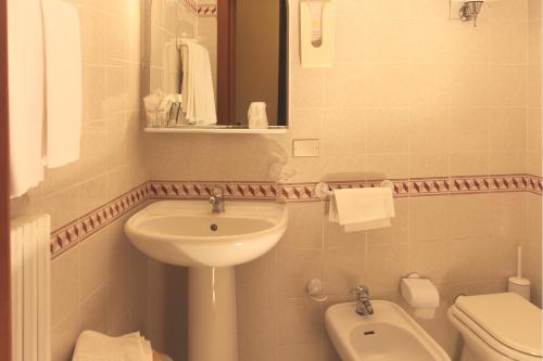 a white bathroom with a sink and a toilet at Hotel Pallotta in Assisi