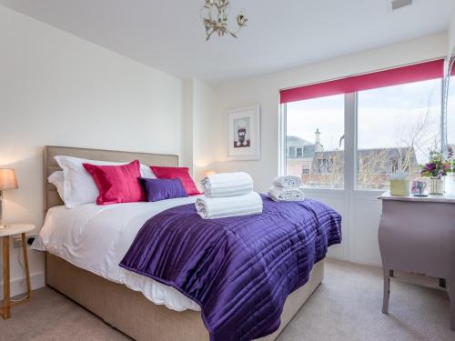 a bedroom with a bed with purple sheets and a window at Time and Tide in Poole