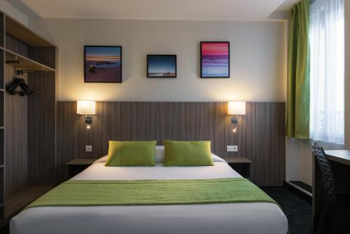 a bedroom with a bed with two green pillows at Reims Hotel in Paris