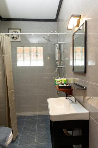 a bathroom with a sink and a mirror and a shower at Oudomsin Guesthouse in Luang Prabang