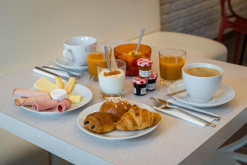 a breakfast table with plates of food and cups of coffee at Reims Hotel in Paris
