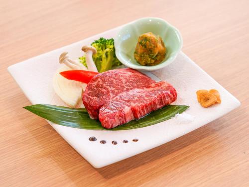 a plate of meat and vegetables on a table at さめうら荘レイクサイドホテル in Tosa