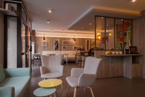 a living room with a couch and chairs and a kitchen at Reims Hotel in Paris