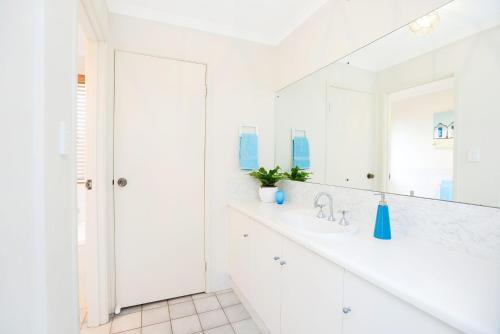 a white bathroom with a sink and a mirror at 2 Marto Court in Normanville