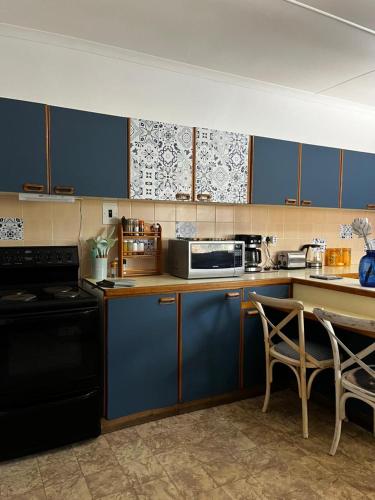 a kitchen with blue cabinets and a counter with a microwave at Casa Bella in Dwarskersbos