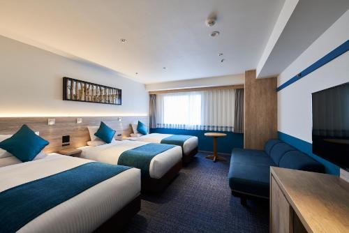 a hotel room with two beds and a flat screen tv at Art Hotel Asahikawa in Asahikawa